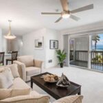 Updated-living-room-photo Bright living room with a beige sectional, coffee table, and ocean-view balcony beyond sliding doors.